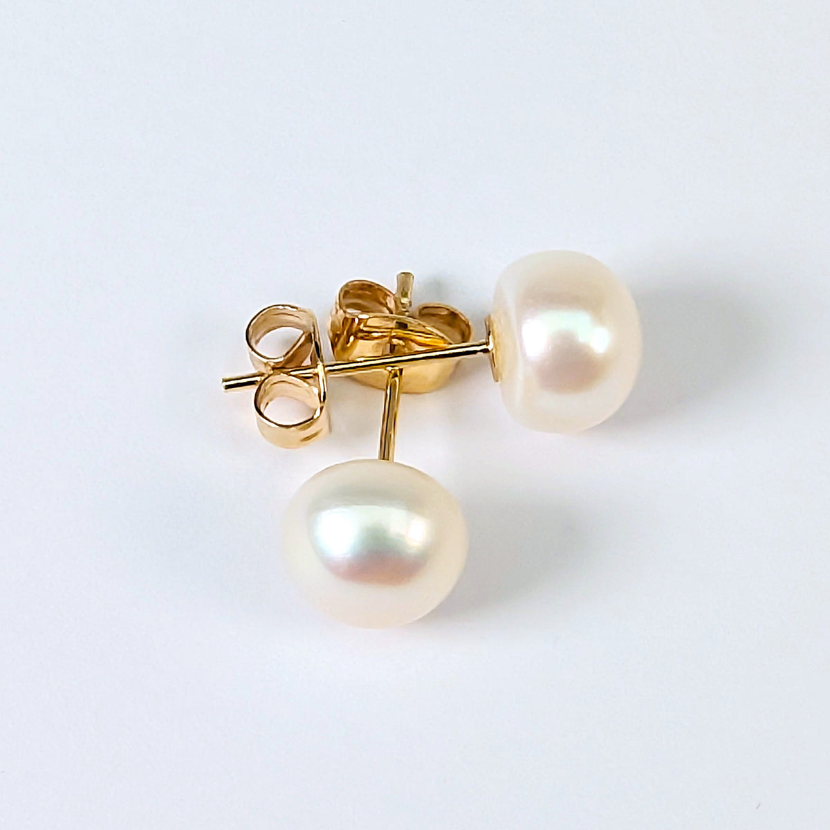 Boucle d'oreille clou Diana en plaqué or 18K avec perle de culture blanche en forme de bouton, environ 7mm, nacrée, posée sur fond blanc