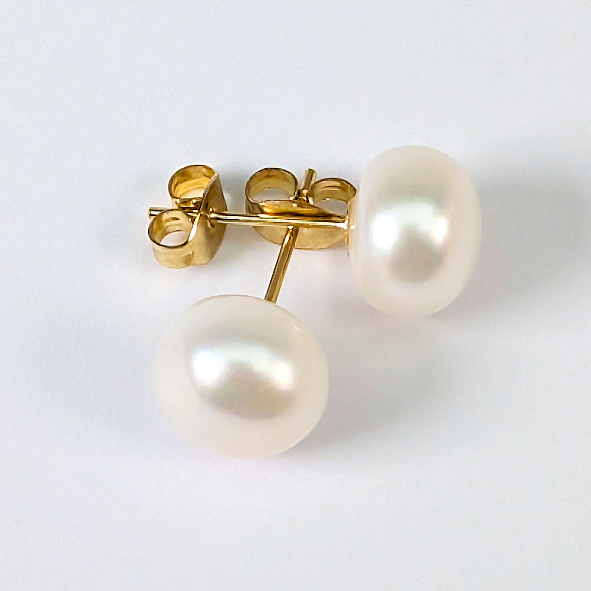 Boucle d'oreille clou Diana en plaqué or 18K avec perle de culture blanche en forme de bouton, environ 9mm, nacrée, posée sur fond blanc