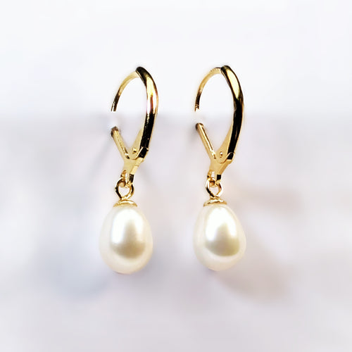 Paire de boucles d'oreilles Aphrodite suspendues, montrant la monture dormeuse en plaqué or 18K et la perle blanche ovale en forme de goutte d'eau
