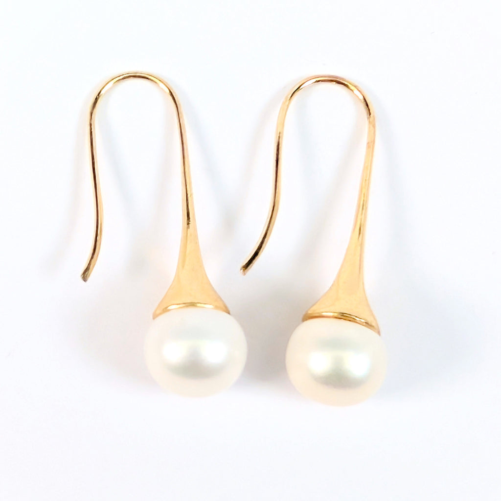 Paire de boucles d'oreilles Aurore posées à plat côte à côte sur fond blanc, montures pendantes en plaqué or 18K et perles blanches en forme de bouton
