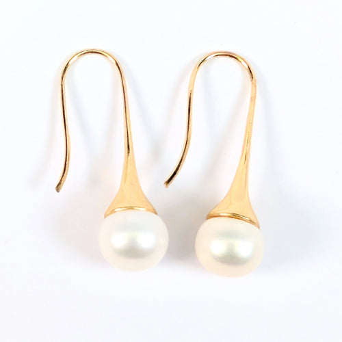 Paire de boucles d'oreilles Aurore posées à plat côte à côte sur fond blanc, montures pendantes en plaqué or 18K et perles blanches en forme de bouton