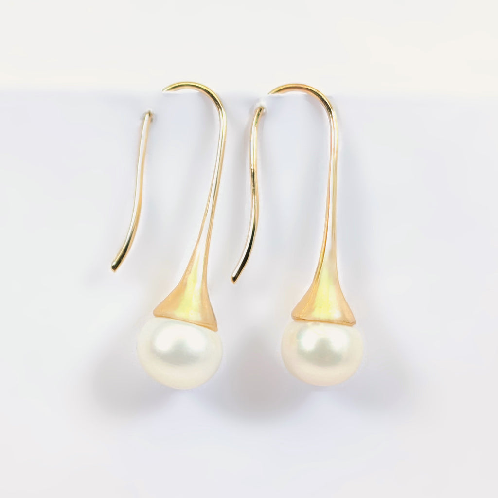 Paire de boucles d'oreilles Aurore suspendues, montrant la monture pendante en plaqué or 18K et la perle blanche en forme de bouton