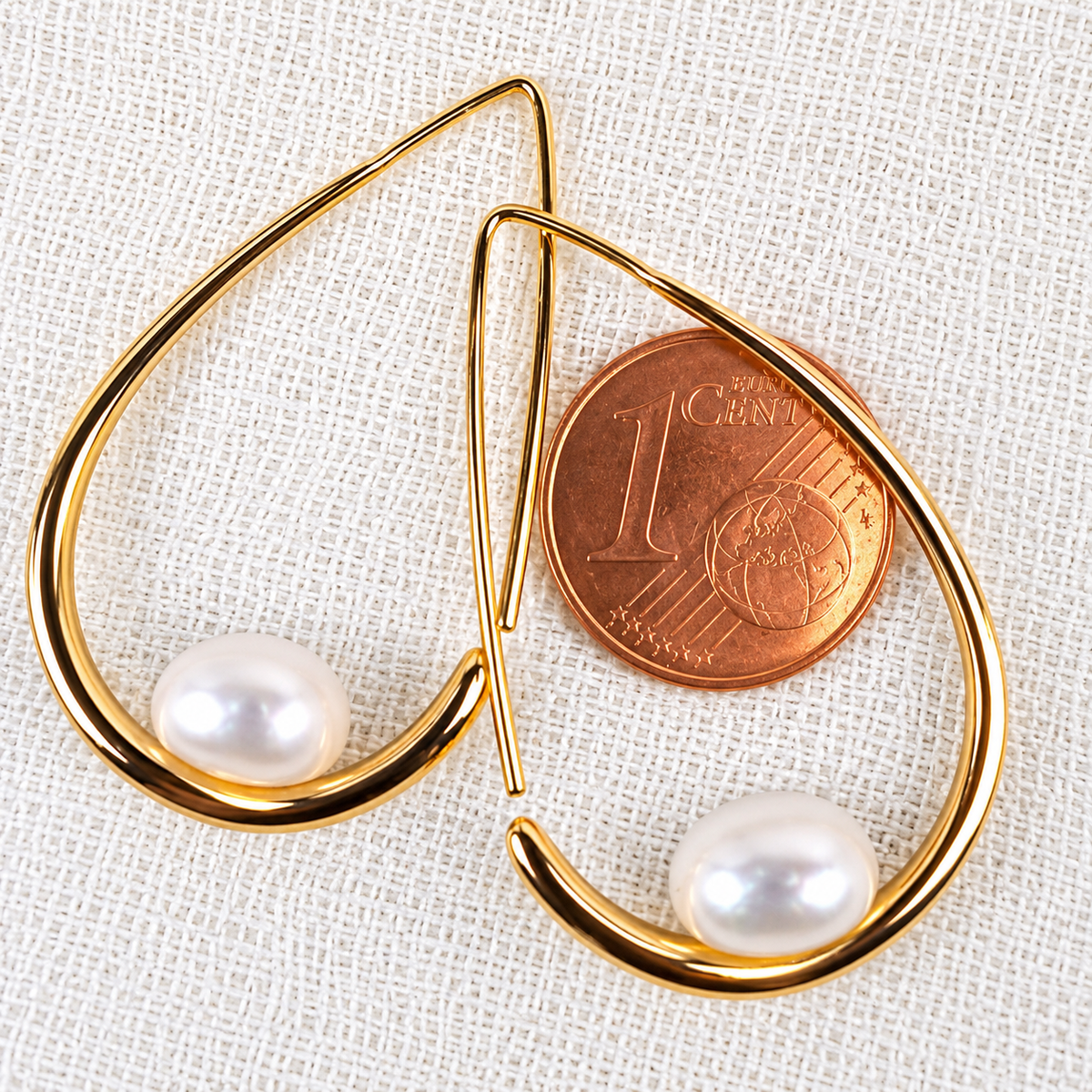 Boucles d'oreilles Calypso à côté d'une pièce d'1 centime pour comparaison de taille, perle de culture blanche en forme de bouton