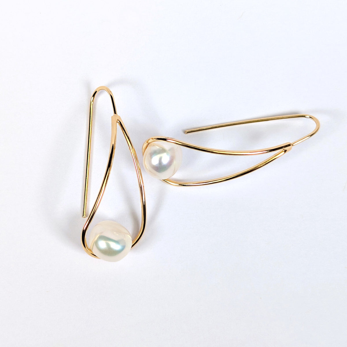 Boucles d'oreilles Sissi croisées, montrant la monture pendante en plaqué or 18K et la perle blanche en forme de bouton