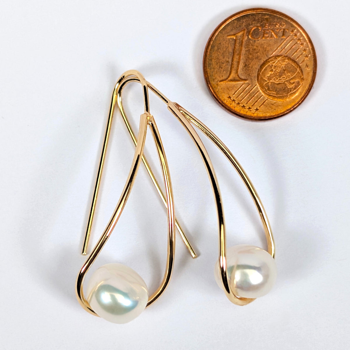 Boucles d'oreilles Sissi à côté d'une pièce d'1 centime pour comparaison de taille, perle de culture blanche en forme de bouton