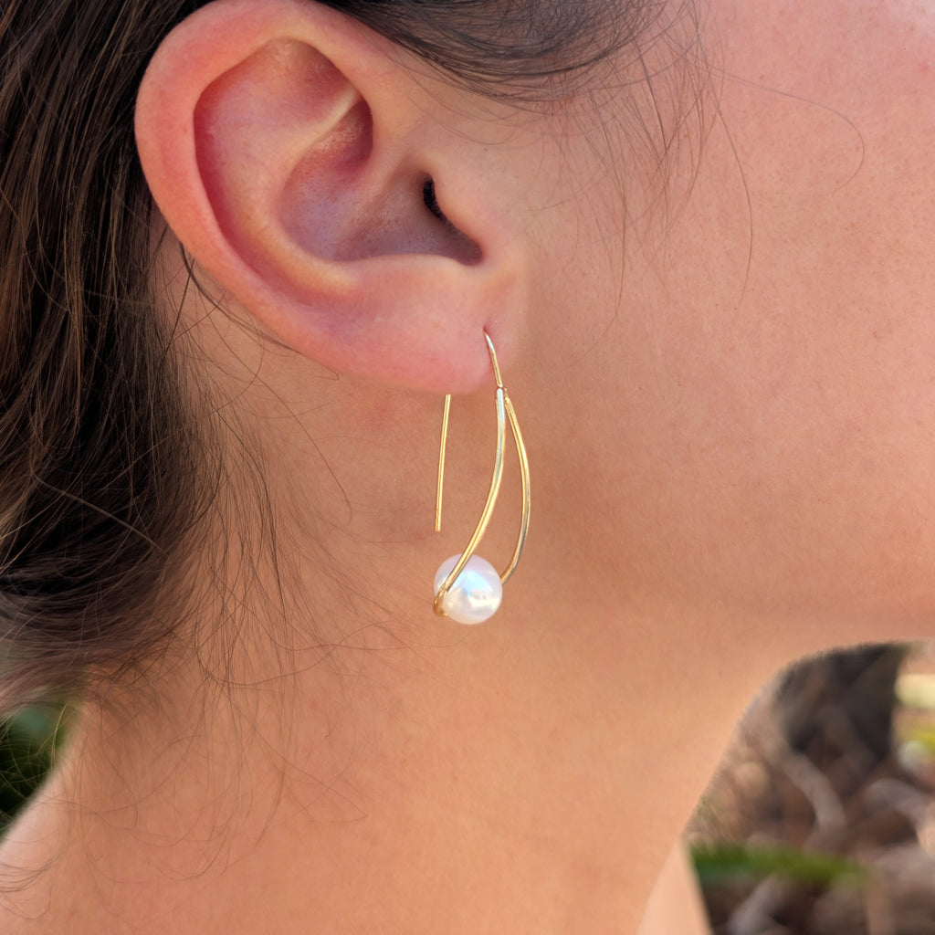 Femme portant une boucle d'oreille Sissi à l'oreille, monture pendante en plaqué or 18K et perle blanche en forme de bouton, vue de profil