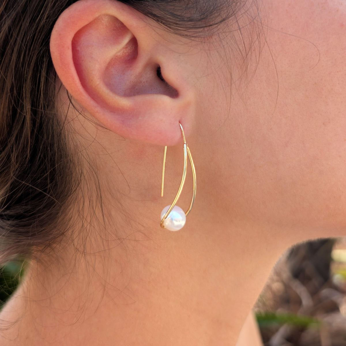 Femme portant une boucle d'oreille Sissi à l'oreille, monture pendante en plaqué or 18K et perle blanche en forme de bouton, vue de profil