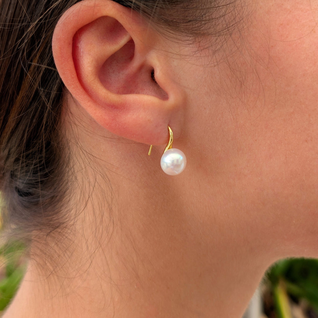 Femme portant une boucle d'oreille Cléopâtre à l'oreille, monture pendante en plaqué or 18K et perle blanche en forme de bouton, vue de profil