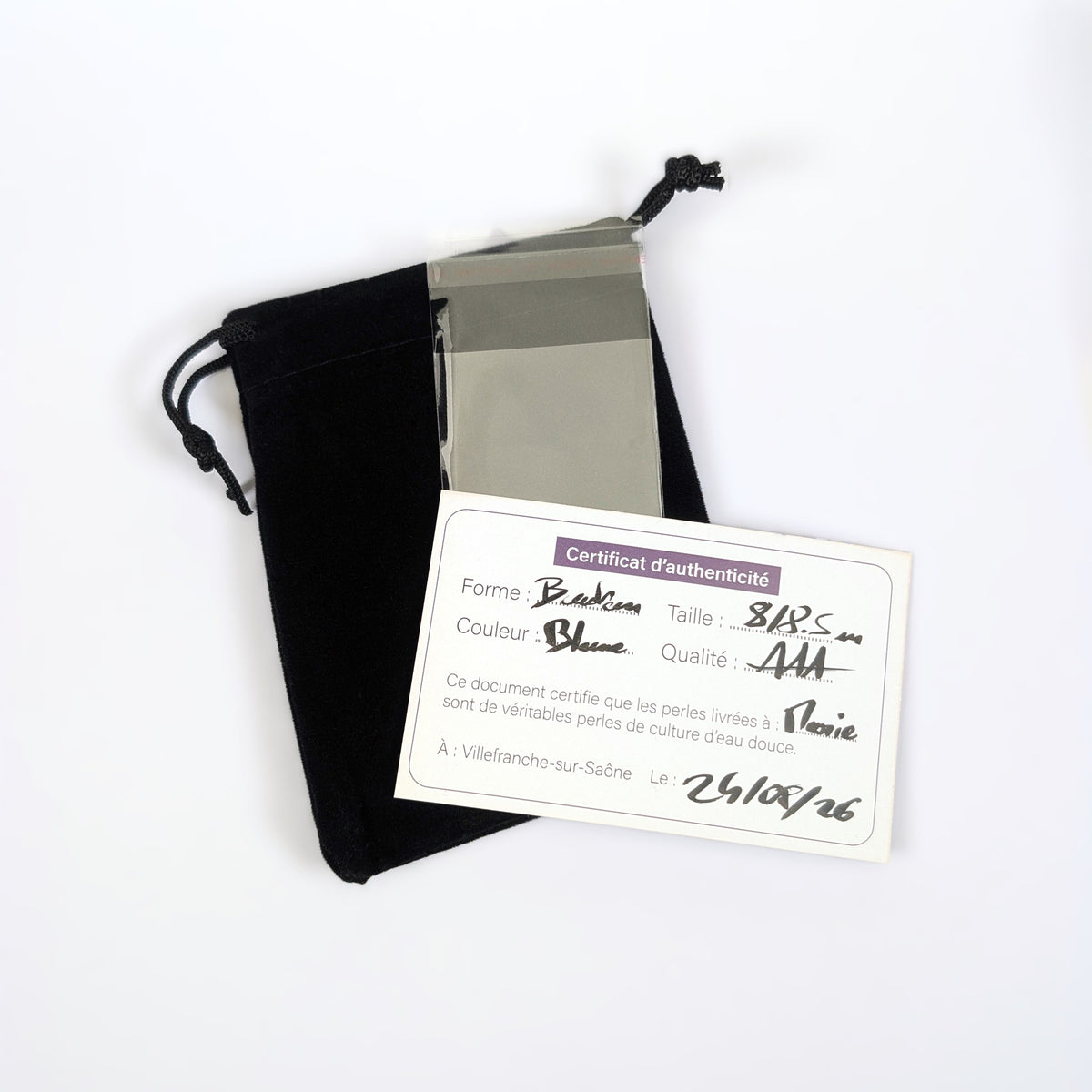 Écrin de présentation L'Atelier de la Perle : pochon en velours noir, certificat d'authenticité manuscrit précisant forme, couleur, taille et qualité de la perle, et pochette de protection transparente